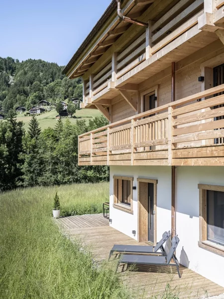 Le chalet ZenSpace vu de côté avec les chaises longues sur la terrasse en été.