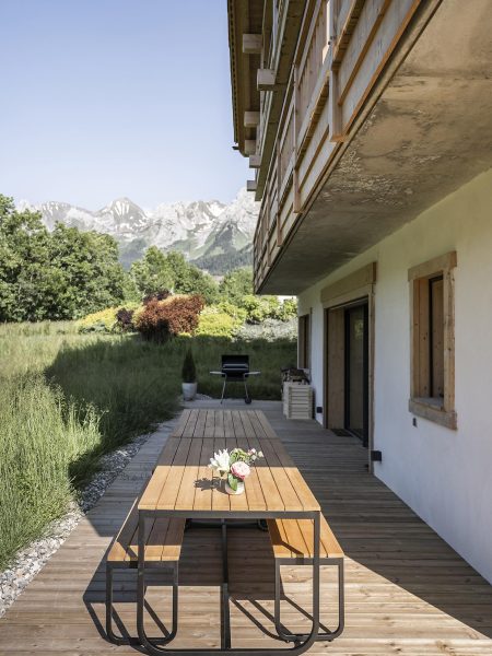 Table en bois extérieure et barbecue sur la terrasse en bois du chalet Zenspace en été